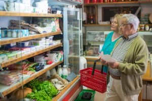 Elderly couple selecting groceries in a supermarket, examining products together.