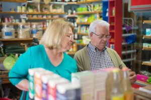 Elderly couple shopping in a cozy grocery store, enjoying a relaxed shopping experience.